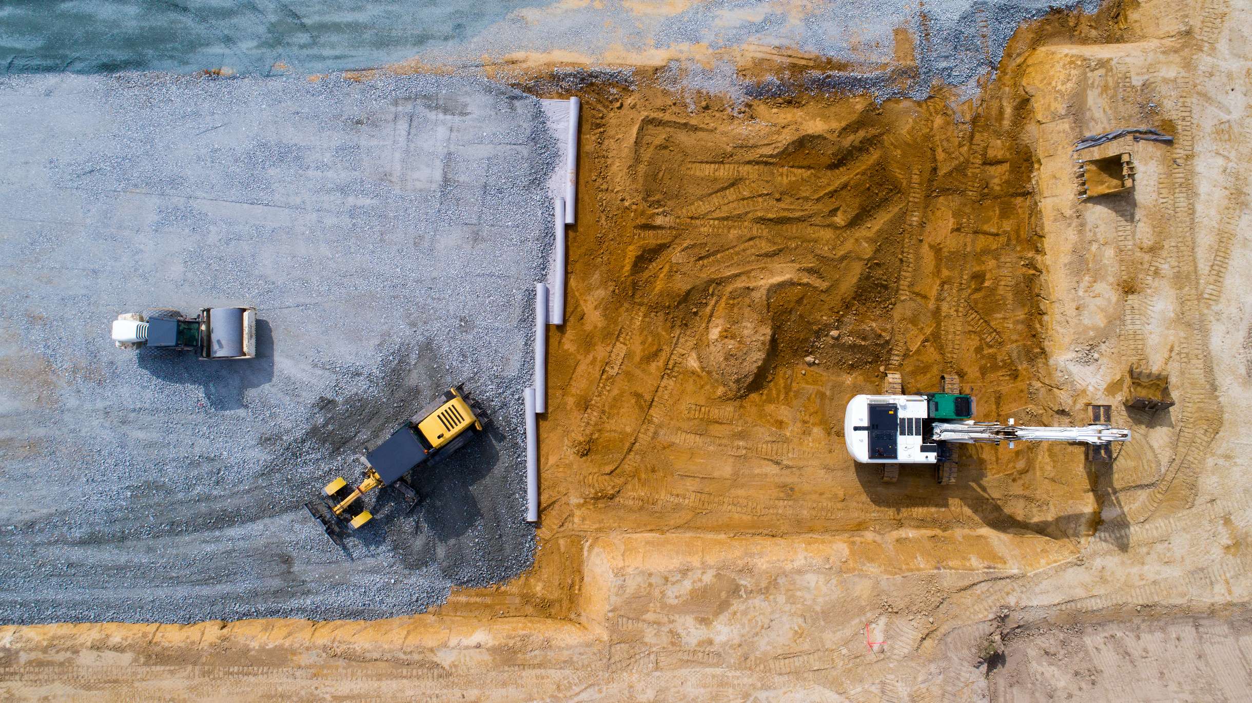 Drohnenaufnahme einer Baustelle mit Bagger und Planierraupe, passend zum Webdesign für die nowiBAU Gruppe.